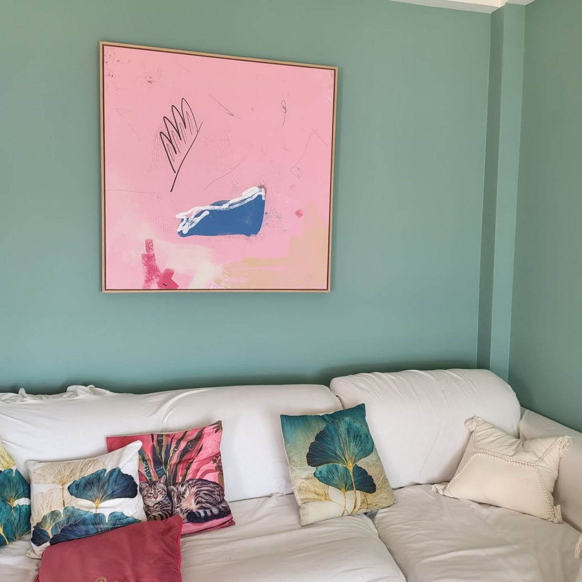 Pink abstract canvas by Jacob Lund above a white sofa against a green wall